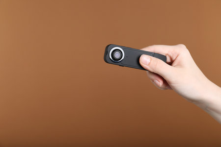 Woman with hidden camera on brown background, closeup. Space for textの写真素材