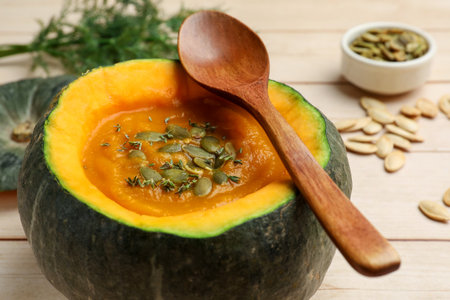 Tasty pumpkin cream soup with seeds and thyme served in pumpkin on wooden table, closeupの写真素材