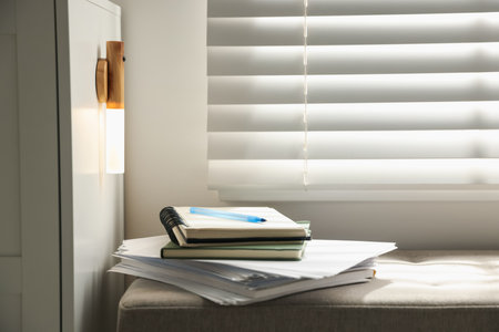 Stack of notebooks on pouf and portable LED lamp at home. Space for textの写真素材