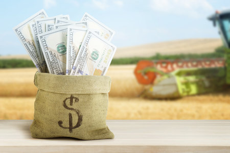 Agricultural production profit. Bag with dollars against combine harvester in fieldの写真素材
