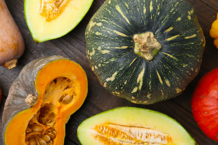 Many fresh pumpkins and melon on wooden table, flat lay. Gourd family
