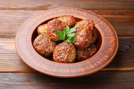 Delicious meat patties with parsley on wooden table, closeup