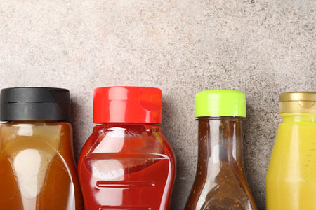 Bottles of different tasty sauces on gray table, flat lay. Space for textの写真素材