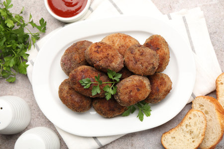 Tasty meat patties served on gray table, flat lay