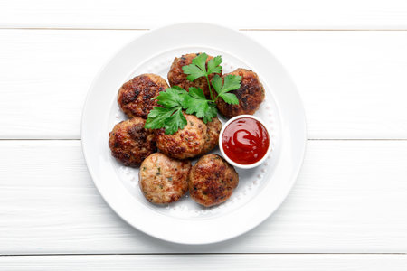 Delicious patties with parsley and ketchup on white wooden table, top viewの写真素材