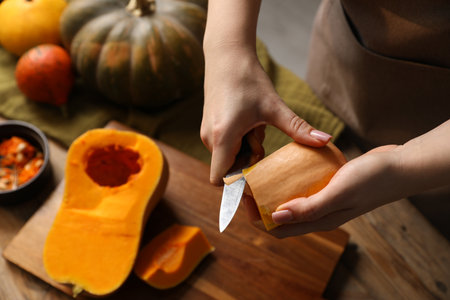 Woman peeling pumpkin at wooden table, above viewの写真素材