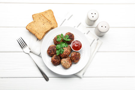 Delicious patties with parsley and ketchup served on white wooden table, flat layの写真素材