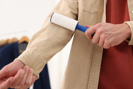 Man cleaning shirt with lint roller at home, closeupの写真素材