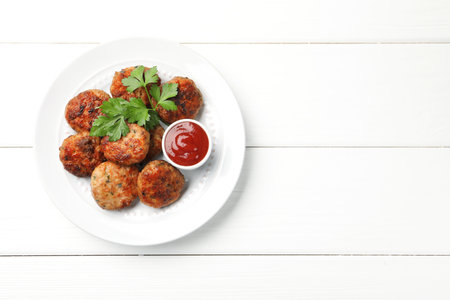 Delicious patties with parsley and ketchup on white wooden table, top view. Space for textの写真素材