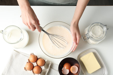 Woman making batter (liquid dough) at white table, top viewの写真素材