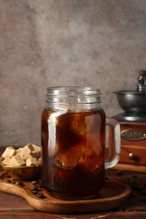 Iced coffee, sugar, grinder and beans on wooden tableの写真素材