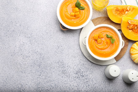 Delicious pumpkin cream soup with basil served on gray table, flat lay. Space for textの写真素材