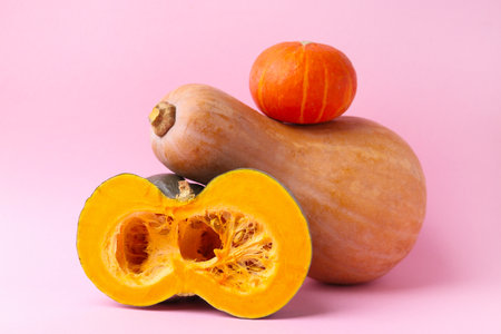 Whole and cut pumpkins on pink background, closeup. Gourd familyの写真素材
