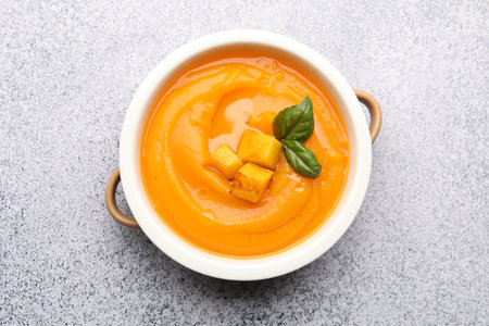 Delicious pumpkin cream soup with basil served on gray table, top viewの写真素材