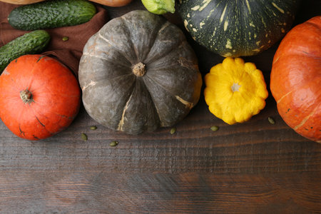 Many fresh pumpkins, seeds and other vegetables of gourd family on wooden table, flat lay. Space for textの写真素材