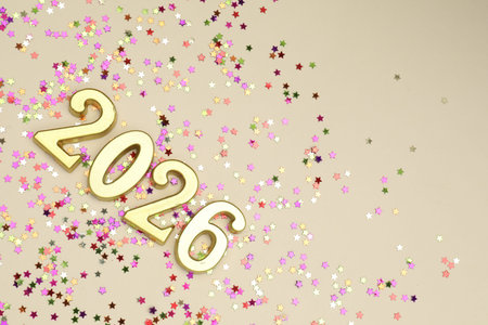 New 2026 Year. Golden numbers and colorful confetti on beige background, flat lay. Space for text
