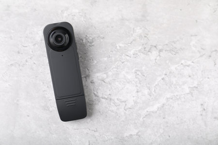 Modern hidden spy camera on light gray table, top view. Space for text