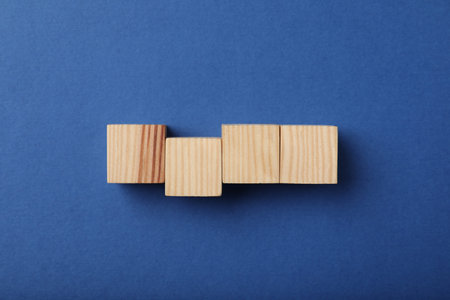 Wooden cubes on blue background, top view