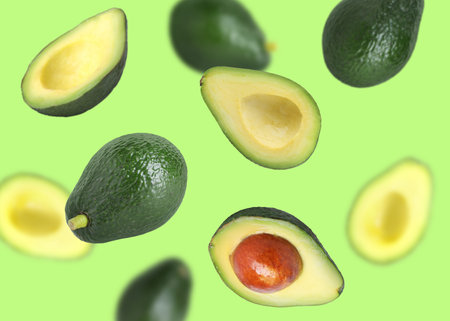 Fresh avocado falling on light green background. Whole and sliced