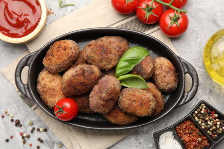 Tasty meat patties served on gray textured table, flat lay