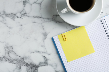 Blank note, notebook and cup of coffee on white marble table, flat lay. Space for textの写真素材