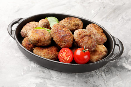 Tasty meat patties with tomatoes on gray textured table