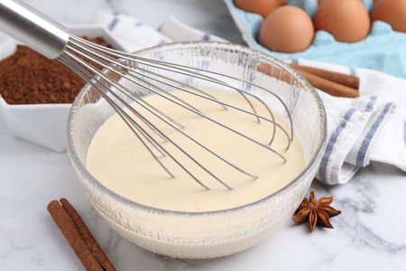 Liquid dough in bowl, ingredients on white table, closeup