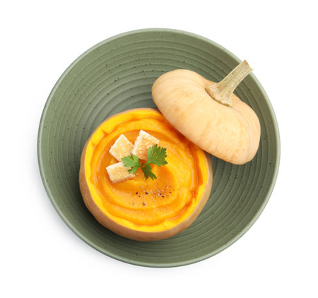 Tasty pumpkin cream soup with parsley and croutons served in pumpkin isolated on white, top viewの写真素材