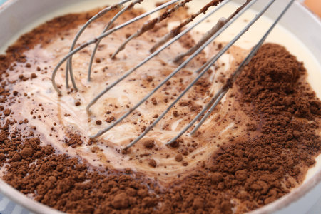 Adding cocoa powder into bowl with dough, closeupの写真素材