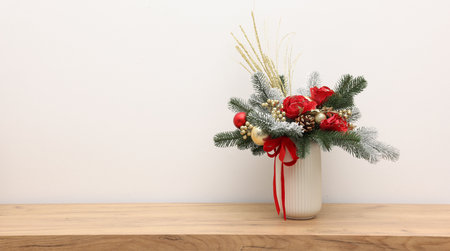 Beautiful composition with fir tree branches in vase on wooden table near white wall indoors, space for text. Winter decorの写真素材
