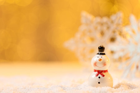 Cute decorative snowman on artificial snow against blurred background. Space for textの写真素材