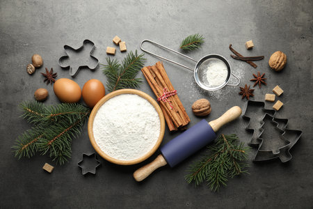 Christmas composition with fir tree branches, cookie cutters and spices on gray table, flat layの写真素材