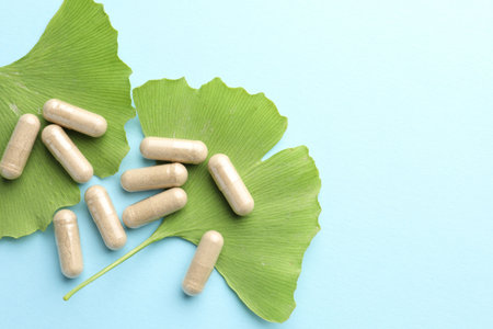 Ginkgo biloba leaves and pills on light blue background, flat lay. Space for textの写真素材