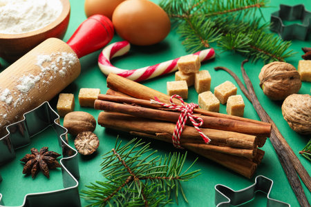 Christmas composition with cookie cutters, fir tree branches and spices on green background, closeupの写真素材