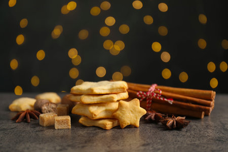 Christmas food. Cookies in shape of stars, spices, brown sugar and fir tree branches on gray table against background with blurred lights, closeup. Bokeh effectの写真素材