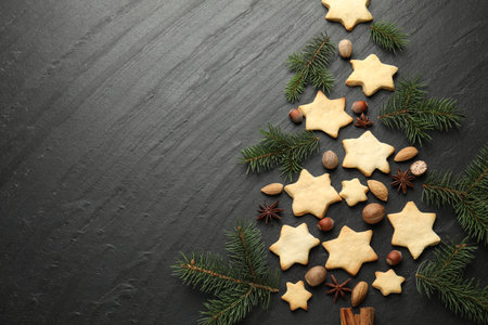 Christmas tree shape made of cookies, fir branches and spices on black table, flat lay. Space for textの写真素材