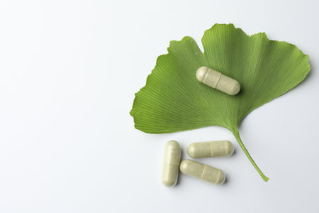 Ginkgo biloba leaf and pills on white background, flat lay. Space for textの写真素材