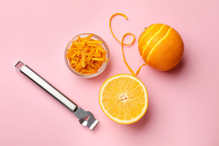 Orange zest, fresh fruits and zester tool on pink background, flat layの写真素材