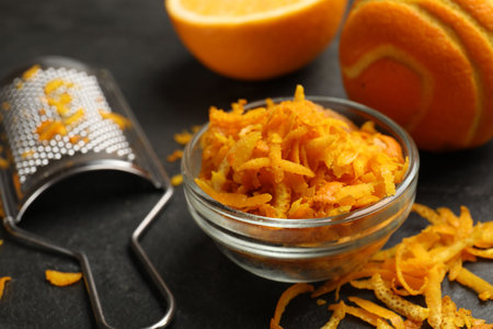 Orange zest, fresh fruit and grater on black table, closeupの写真素材