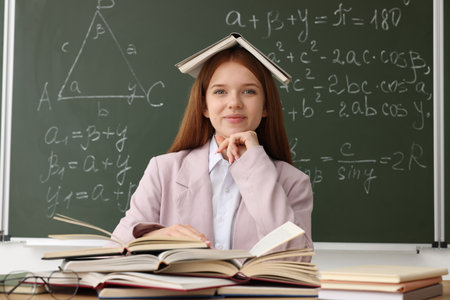 Back to school. Student with books at desk against chalkboard with math assignment indoorsの写真素材