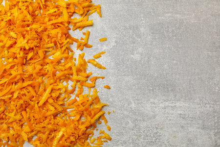 Fresh orange zest on light gray table, flat lay. Space for text