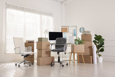 Moving day. Cardboard boxes, computer and furniture in officeの写真素材