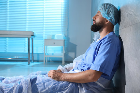 Tired doctor near wall in clinic during night shiftの写真素材