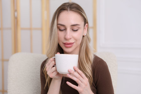 Woman enjoying tasty cocoa drink at homeの写真素材