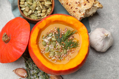 Tasty pumpkin cream soup with seeds, herbs, garlic and bread on gray textured table, flat layの写真素材
