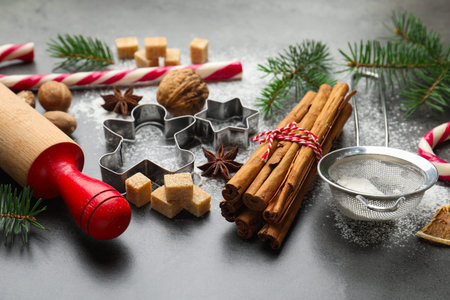 Christmas composition with fir tree branches, rolling pin, cookie cutters and spices on gray table,...