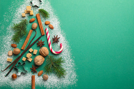 Christmas tree shape made with cookies, spices and fir branches on green background, flat lay. Space for textの写真素材