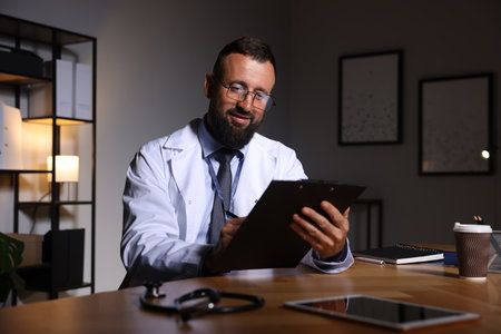 Doctor writing notes at table in clinic during night shiftの写真素材