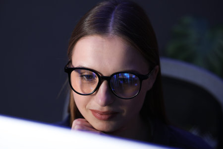 Young woman wearing glasses with reflection in dark room