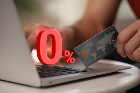 Man with credit card using laptop at table, closeup. 0 percent sign for zero commission